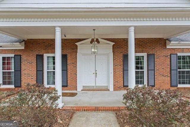 entrance to property featuring covered porch and brick siding