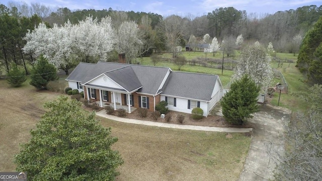 view of front of house featuring driveway, covered porch, and a front lawn