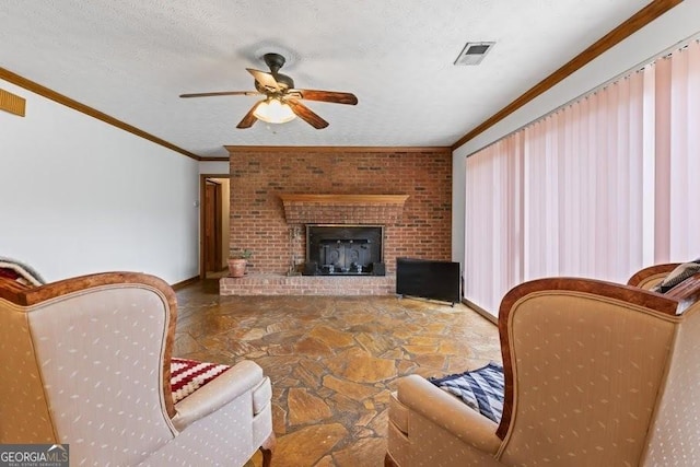 living room featuring visible vents, a ceiling fan, ornamental molding, a textured ceiling, and a fireplace