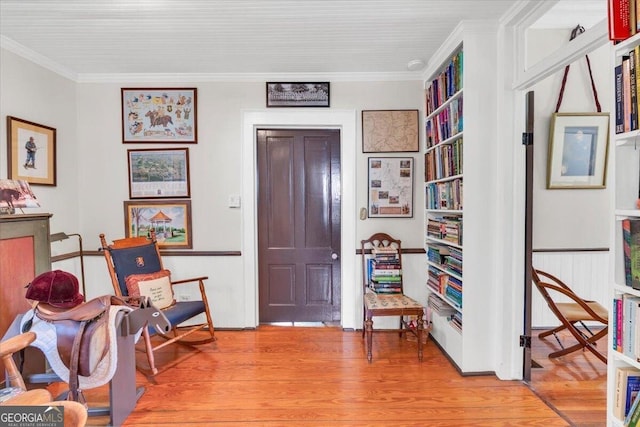 sitting room featuring crown molding and light wood-style flooring