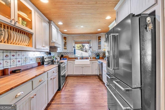 kitchen with decorative backsplash, wood ceiling, appliances with stainless steel finishes, wooden counters, and a sink