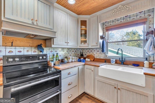 kitchen featuring custom exhaust hood, light countertops, backsplash, a sink, and double oven range