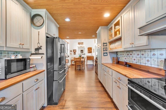 kitchen with wooden ceiling, under cabinet range hood, butcher block counters, and appliances with stainless steel finishes