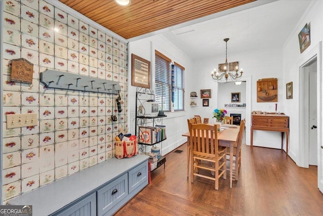 dining space with wooden ceiling, a fireplace, an inviting chandelier, dark wood finished floors, and crown molding