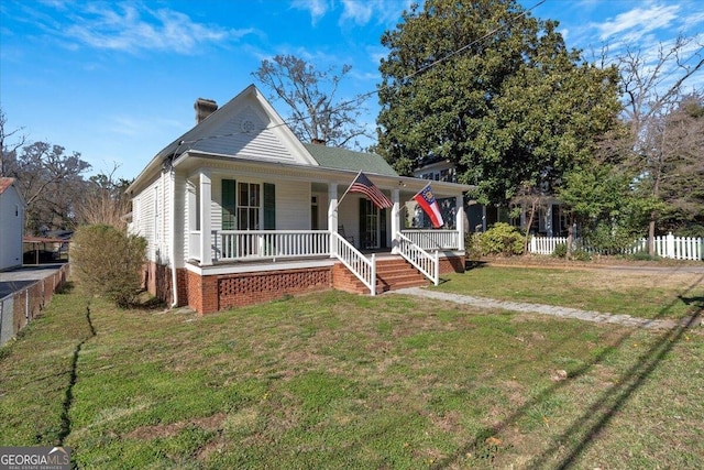 bungalow featuring a porch, fence, a chimney, and a front lawn