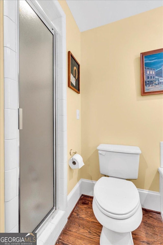 full bath featuring a stall shower, baseboards, and wood finished floors