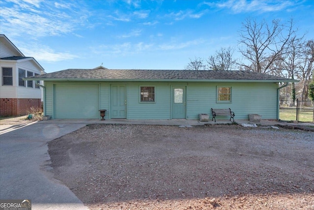 single story home featuring driveway, roof with shingles, an attached garage, and fence