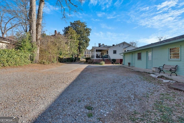 view of yard with driveway and covered porch