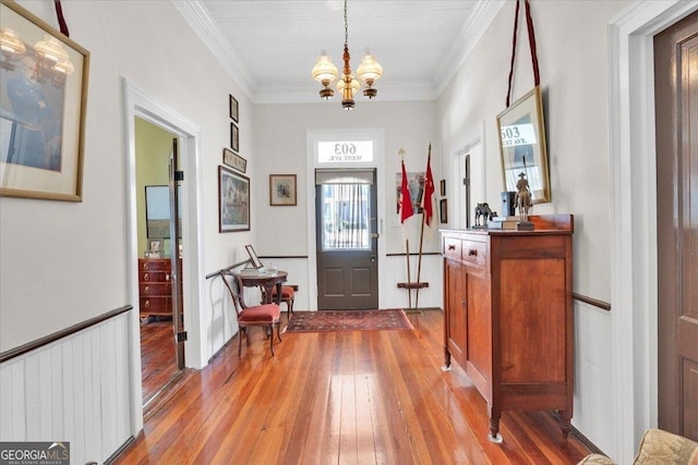 foyer with hardwood / wood-style flooring, ornamental molding, and a notable chandelier