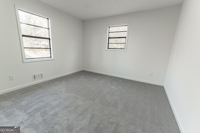 carpeted empty room with visible vents and baseboards