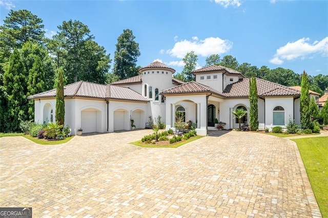 mediterranean / spanish home with a garage, a tile roof, driveway, and stucco siding