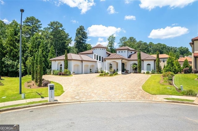 mediterranean / spanish house with a tiled roof, decorative driveway, and a front yard