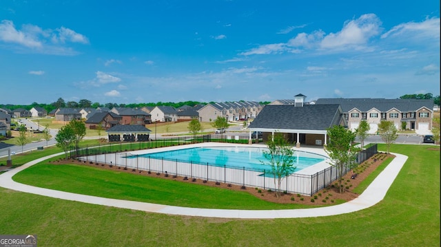 community pool with a residential view, a yard, and fence