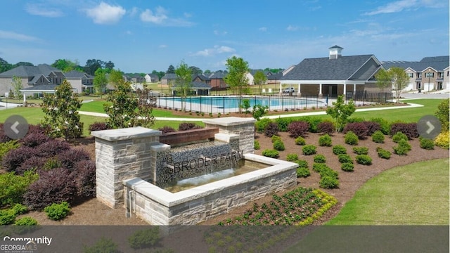 view of community with a yard, a residential view, fence, and a swimming pool