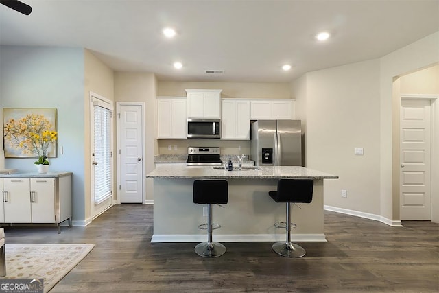 kitchen with stainless steel appliances, visible vents, white cabinetry, dark wood-style floors, and a center island with sink