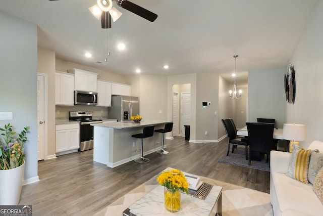 kitchen featuring a kitchen island, dark wood finished floors, white cabinets, appliances with stainless steel finishes, and a kitchen bar