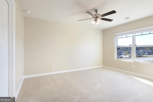 empty room with light carpet, a ceiling fan, and baseboards