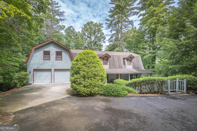 colonial inspired home featuring concrete driveway, a shingled roof, an attached garage, and a gambrel roof