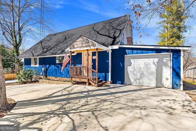 view of front of home featuring concrete driveway, roof with shingles, fence, and an attached garage