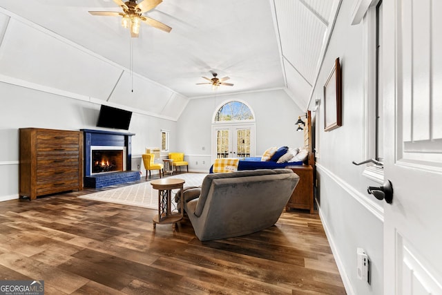 living area featuring french doors, a fireplace, a ceiling fan, vaulted ceiling, and wood finished floors