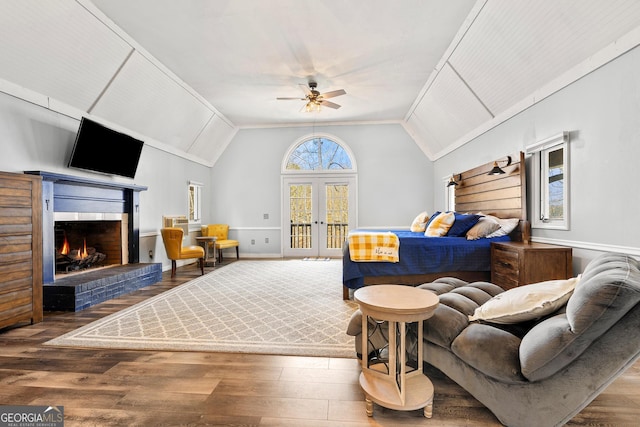 interior space with french doors, a fireplace, lofted ceiling, a ceiling fan, and wood finished floors