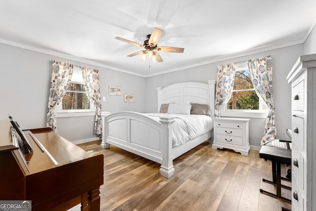 bedroom with a ceiling fan, light wood-type flooring, crown molding, and baseboards