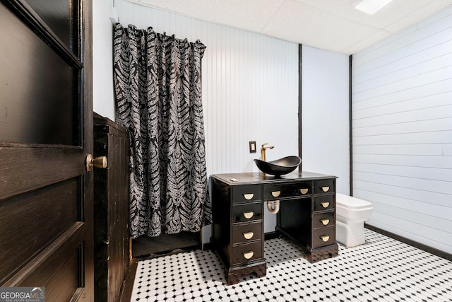 full bath featuring toilet, wooden walls, a drop ceiling, and vanity