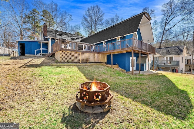 rear view of house with a yard, a chimney, a fire pit, and a wooden deck