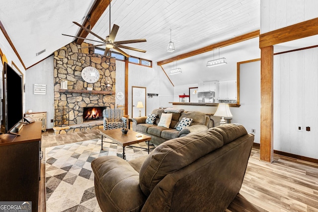 living room with vaulted ceiling with beams, a fireplace, visible vents, a ceiling fan, and light wood-type flooring