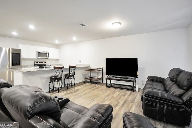 living area with light wood-style floors, recessed lighting, visible vents, and baseboards