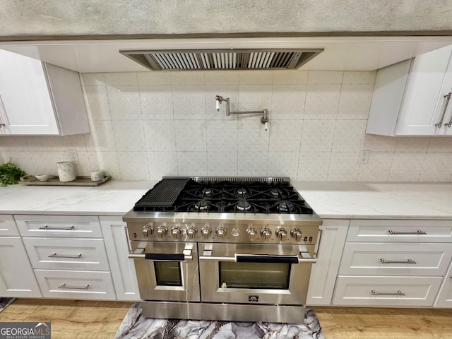 kitchen with light wood-style floors, double oven range, white cabinetry, and light stone counters