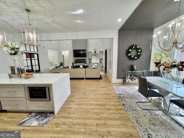 kitchen with a chandelier, light stone counters, beverage cooler, light wood-style floors, and pendant lighting