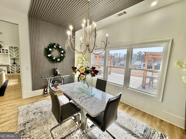 dining room with a chandelier, visible vents, baseboards, and wood finished floors