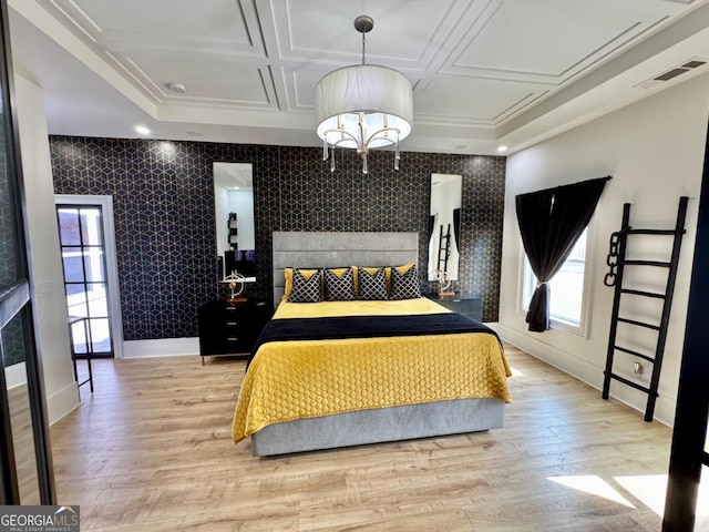 bedroom featuring visible vents, an accent wall, wood finished floors, coffered ceiling, and baseboards