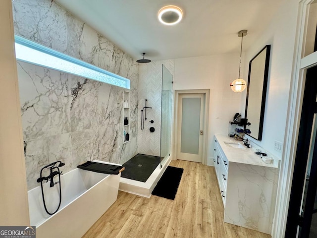 bathroom with double vanity, a sink, wood finished floors, a tub, and walk in shower