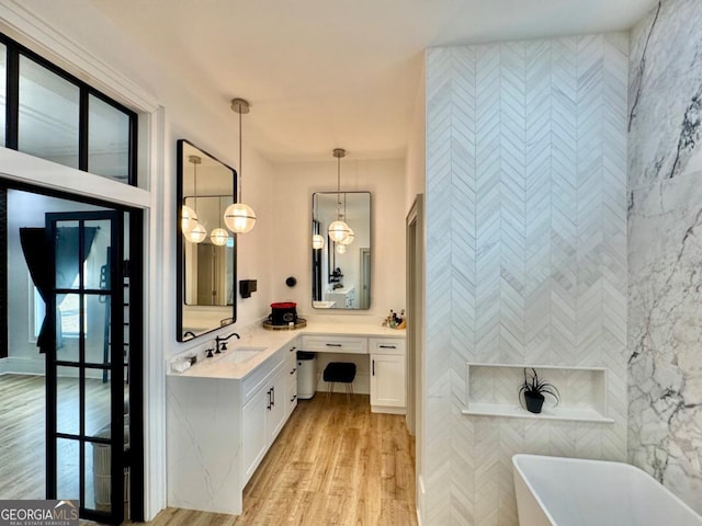 full bath with a freestanding tub, tile walls, wood finished floors, and vanity