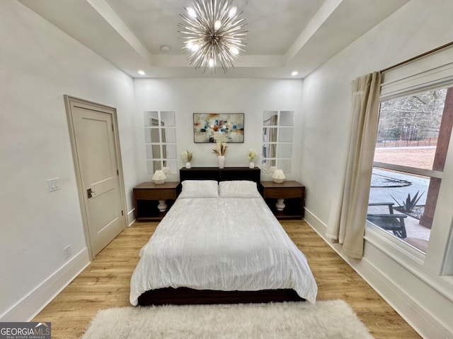 bedroom featuring light wood finished floors, baseboards, a raised ceiling, a notable chandelier, and recessed lighting