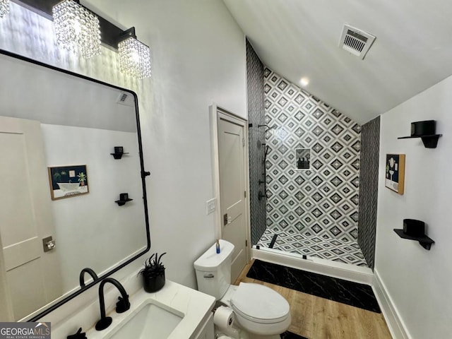 full bathroom with toilet, wood finished floors, vanity, visible vents, and a tile shower