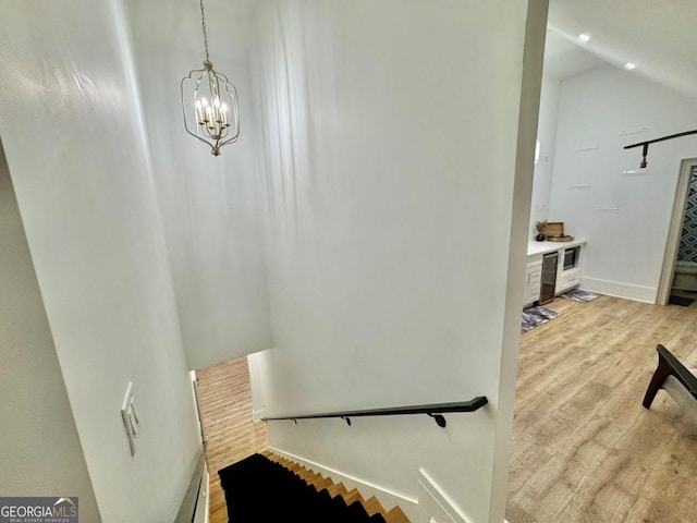 stairs featuring a chandelier, lofted ceiling, baseboards, and wood finished floors