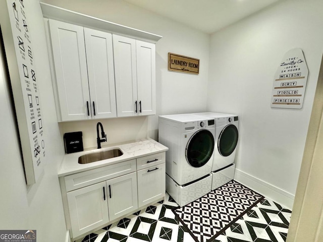 clothes washing area featuring washer and dryer, cabinet space, a sink, and baseboards