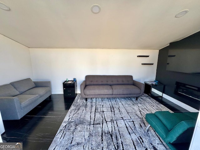 living area featuring vaulted ceiling and baseboards