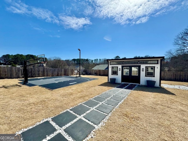 view of basketball court with a yard, fence, and basketball court