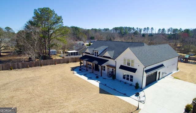 exterior space with driveway, a patio, fence, and roof with shingles