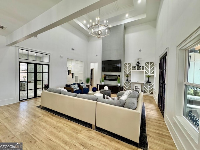 living area with light wood finished floors, baseboards, visible vents, an inviting chandelier, and beam ceiling