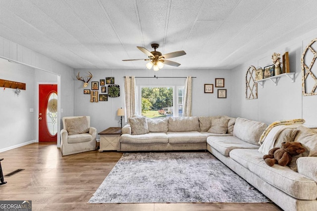 living room featuring ceiling fan, a textured ceiling, and wood finished floors