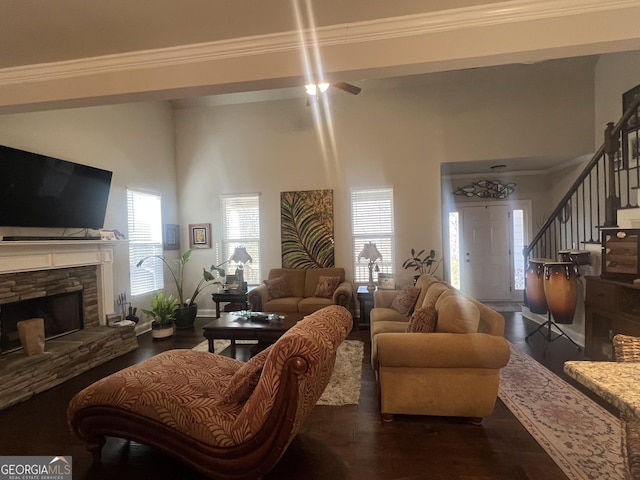 living area featuring ornamental molding, a wealth of natural light, a fireplace, and stairway