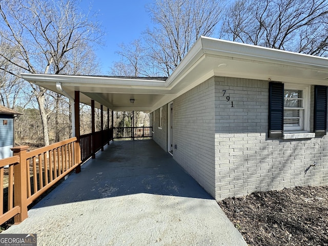 view of side of home with driveway, a carport, and brick siding