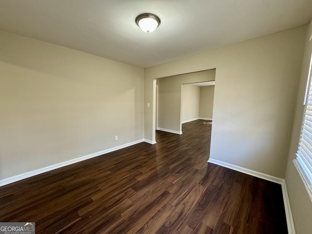 spare room with dark wood-type flooring and baseboards