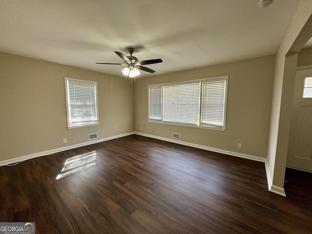 interior space with multiple windows, dark wood finished floors, visible vents, and baseboards