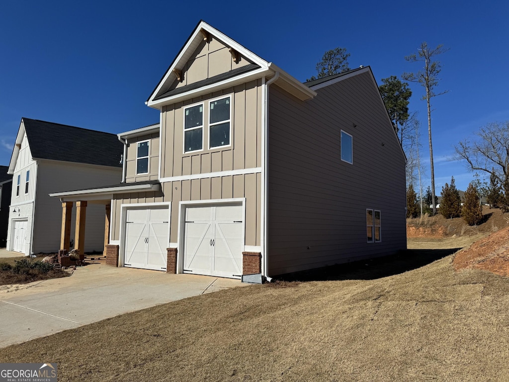 view of side of property with board and batten siding, concrete driveway, brick siding, and an attached garage